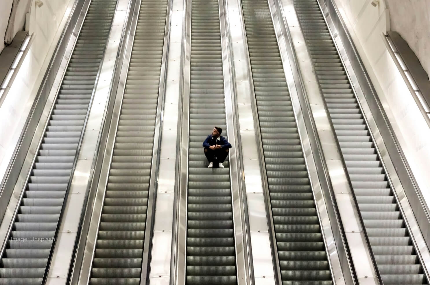 man-sitting-on-escalators-going-up.jpg