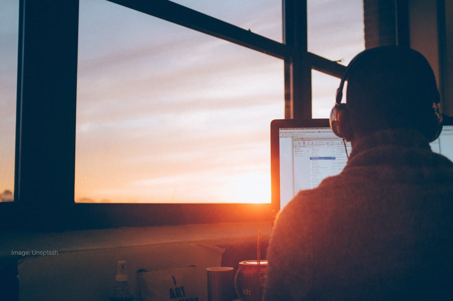 man-with-headphones-on-computer-sunset-in-distance.jpg