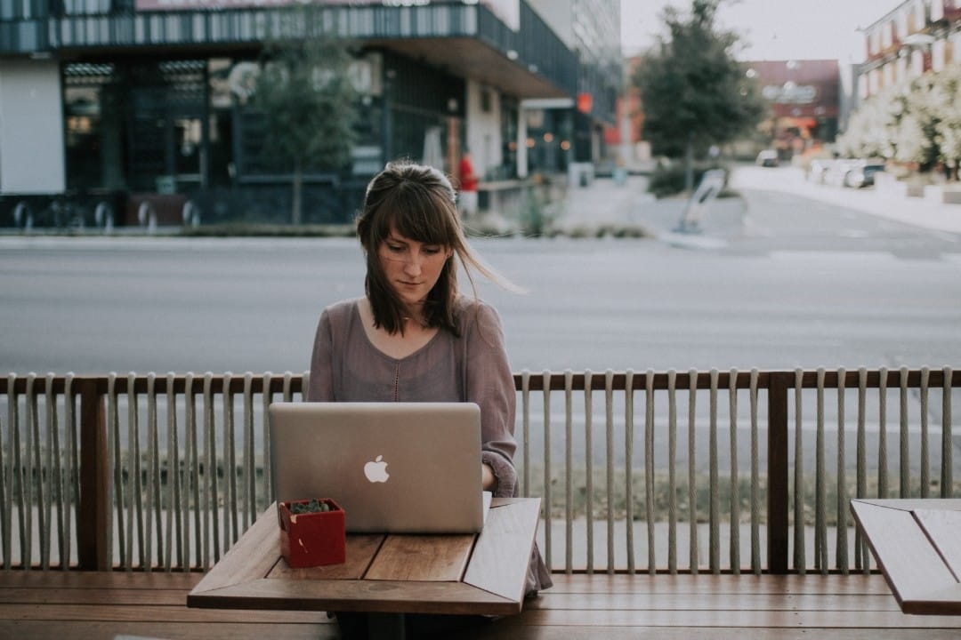lady-with-laptop-at-restaurant-street-in-background.jpg