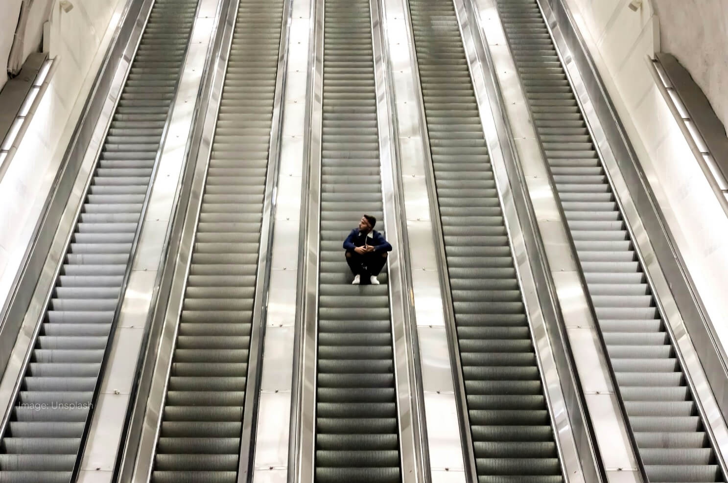 man-sitting-on-escalators-going-up.jpg