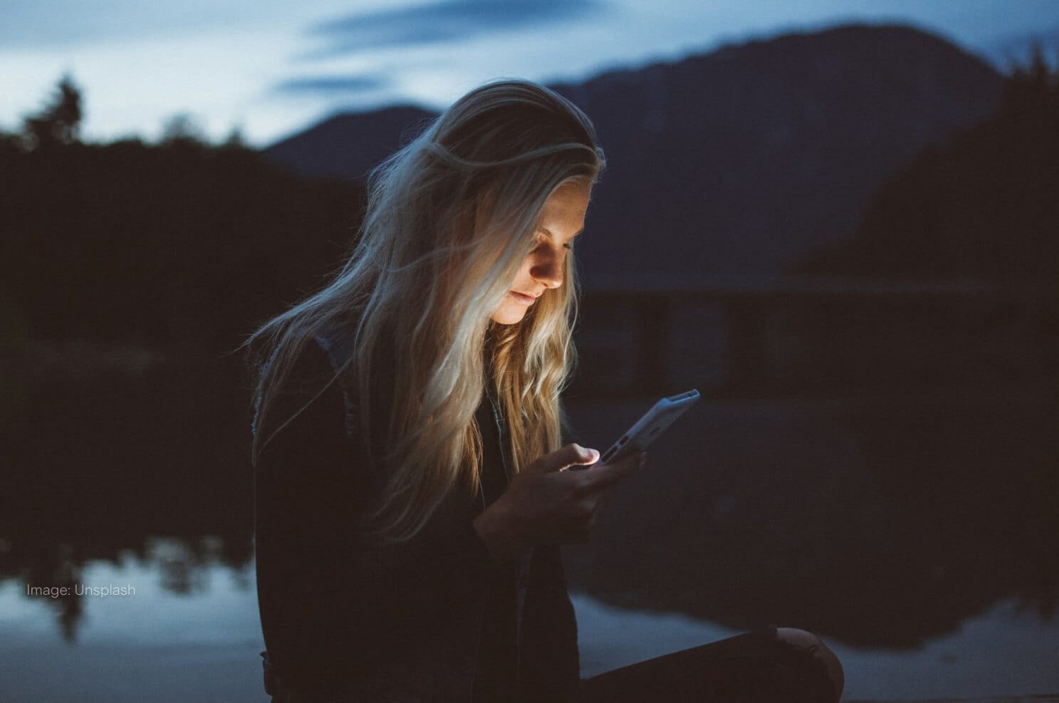 woman-on-phone-at-night-lake-in-background.jpg