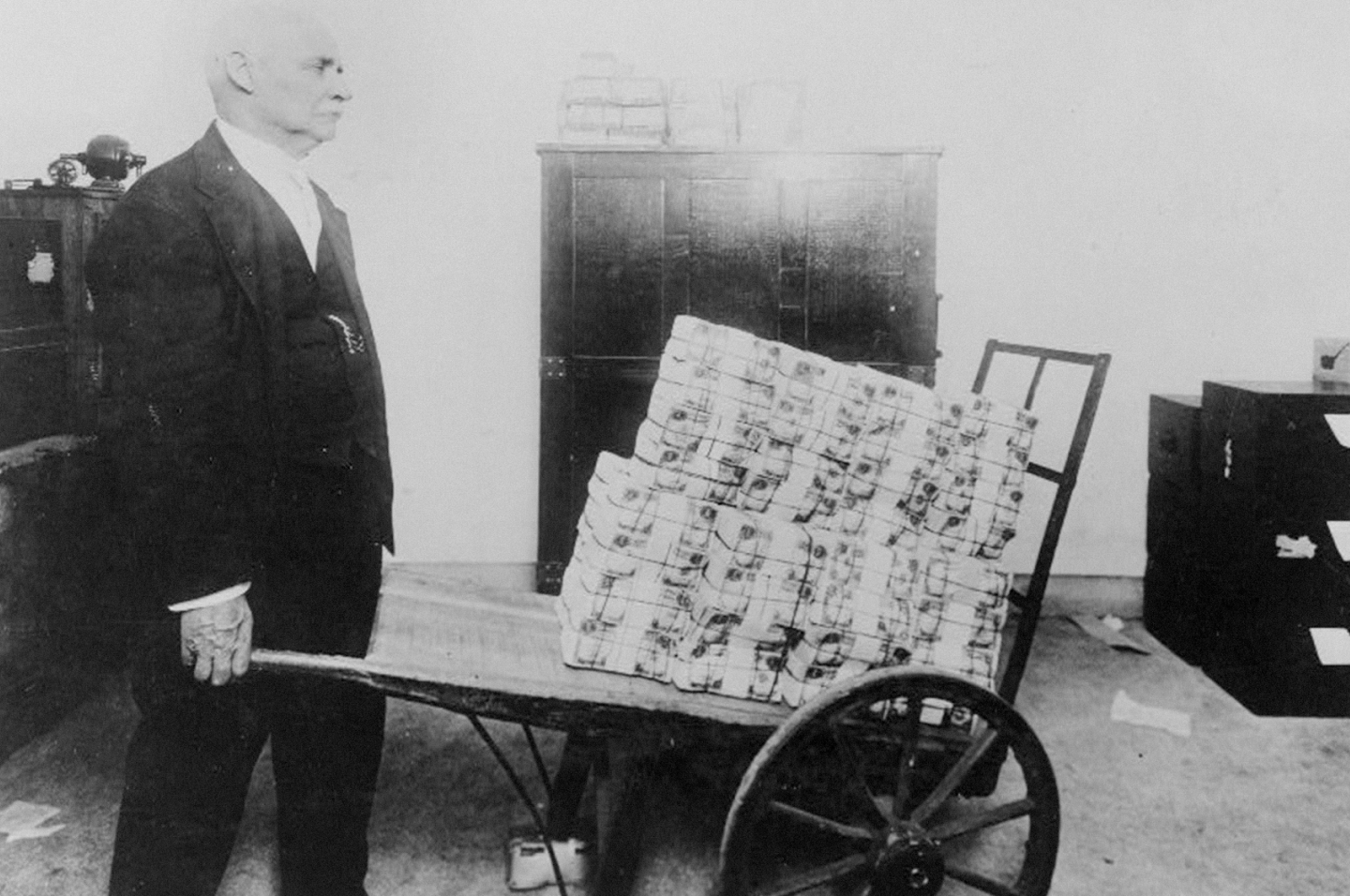 An older gentleman wheeling a cart loaded with cash